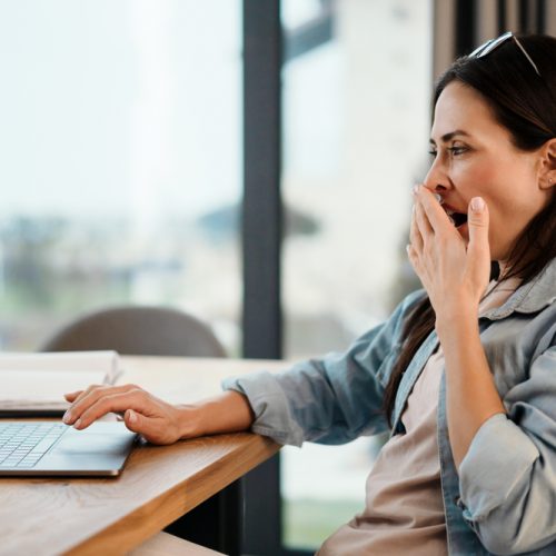 woman yawning researching on computer does adrenal fatigue cause insomnia